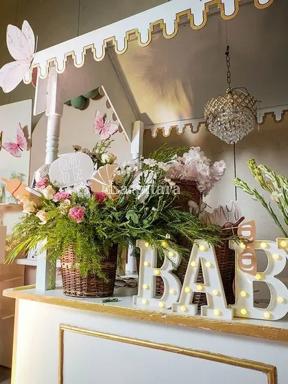 A 'Wishing Well' and bar station at a 'Baby in Bloom' shower, featuring marquee 'BABY' letters and pastel decor.