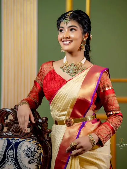 A happy and graceful shot of Amrutha Prem. The combination of the cream saree and red blouse is a classic that never goes out of style.