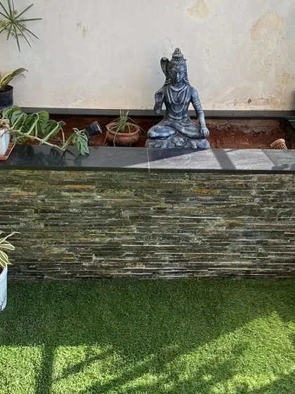A stone statue of Lord Shiva sits peacefully at the edge of a custom-built pond on a balcony. This element transforms the urban space into a personal sanctuary for devotion and tranquility.