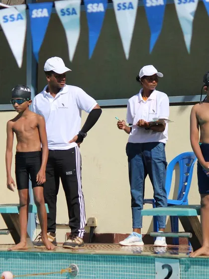 A coach provides last-minute guidance to young swimmers before their race begins.