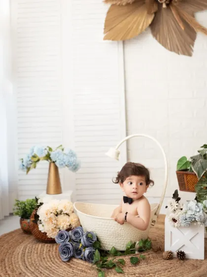 A little boy in a bowtie has fun in a basket during his milestone session. We use simple props to create classic and charming portraits.