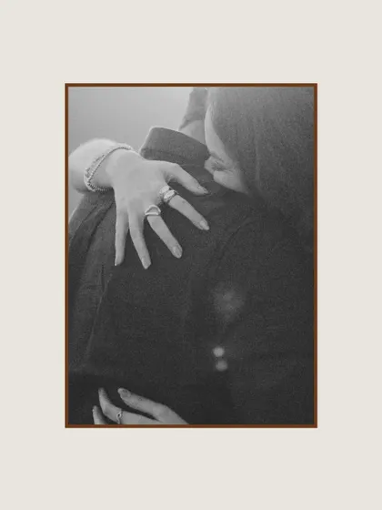 A close-up, black and white shot focusing on the bride's hands as she embraces the groom. This detailed, intimate photo highlights the tenderness and connection in a simple gesture.