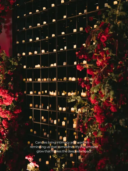 A stunning wall installation featuring hundreds of candles set in a black grid. This dramatic feature served as a dynamic, living backdrop that glowed with warmth and intimacy.