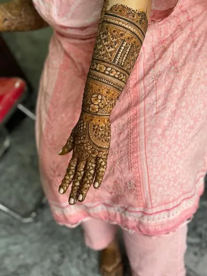 An intricate design on the back of the hand and arm, featuring geometric bands and detailed filler work.