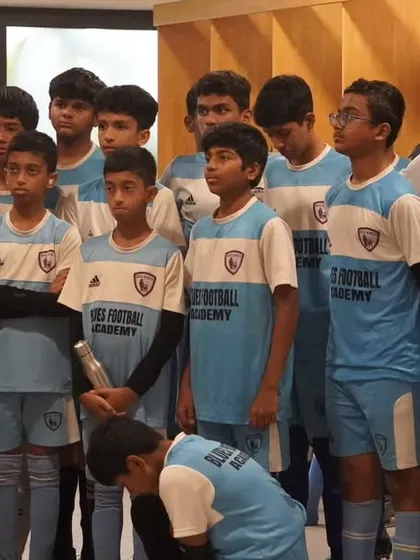 A coach gives a pre-game talk in the locker room, fostering focus and team unity before the players take the field.