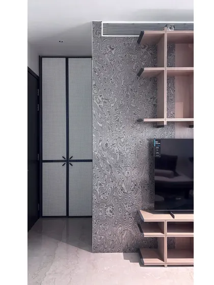 A detail shot of the multipurpose room, showing the textured wallpaper next to the custom shelving unit. The combination of different textures and materials adds depth and character to the space.
