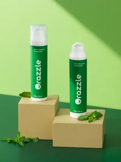 This hero shot for Orazzle toothpaste uses geometric blocks and fresh mint leaves to create a clean, modern composition. The two-tone green background complements the product's branding perfectly.