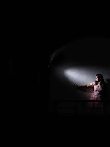 An artistic and dramatic portrait of a bride on her cocktail night. The creative use of light highlights her silhouette against the darkness, creating a mysterious and captivating image.
