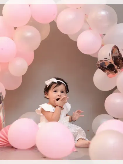 A sweet baby girl surrounded by a beautiful arch of pink balloons. This setup is perfect for creating soft and dreamy milestone portraits.