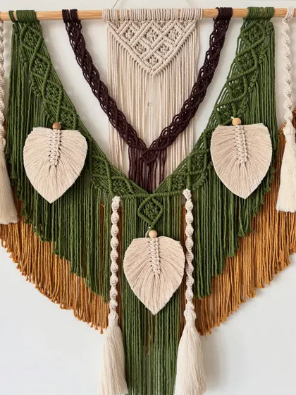 The full view of this V-shaped wall hanging shows the symmetry of the design, with macrame leaves and tassels balanced on each side.