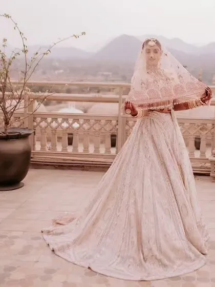 The bride looking like a vision in her ivory Payal Keyal lehenga, with the beautiful hills of Jaipur in the background.