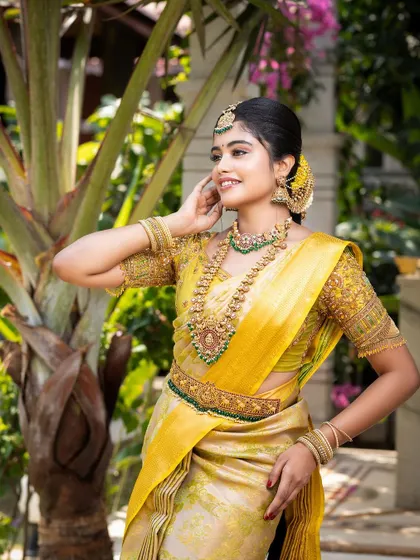 The model's pose highlights the vaddanam and the layers of necklaces, completing the traditional ensemble.