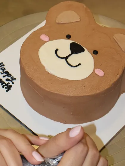 A full view of our teddy bear shaped cake, ready for a "Happy 1 Month" message. The smooth chocolate frosting and cute features make it an instant favorite.