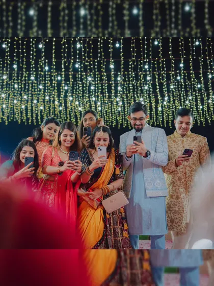 A candid shot of guests capturing the wedding moments on their phones, showing the shared joy of the event.