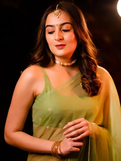 A beautiful portrait in a light green saree with traditional jewelry. The warm backlighting creates a soft, dreamy glow.