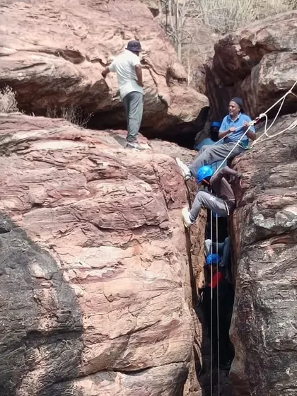 A team works together to manage ropes during a chimney climbing and rappelling exercise.