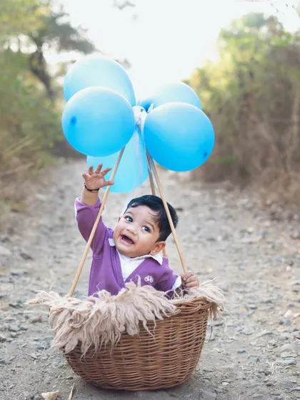 A joyful moment as he reaches for the balloons. Outdoor sessions are great for capturing energetic and playful shots.
