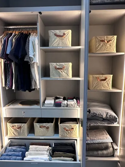 This beautifully lit wardrobe shows the perfect balance between hanging clothes and using bins for folded items. This approach makes a closet highly functional and easy to maintain.