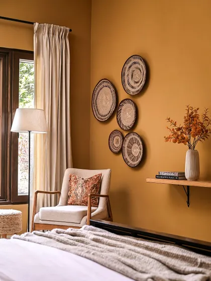 This cozy corner in a bedroom from my Modern Spanish project shows how I use color and texture to create warmth. The mustard-colored wall, woven wall decor, and soft textiles come together to create a calm and inviting reading nook.