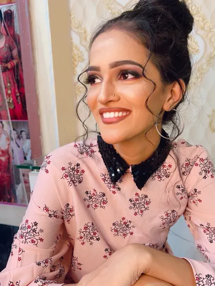 A soft and pretty party look with a messy bun and face-framing curls. The makeup is subtle with a focus on smokey eyes and a nude lip.