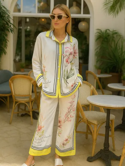 Step out in this stunning printed co-ord set, perfect for a brunch date or a summer evening. The design features a beautiful floral print on a white base, with bold yellow and black striped accents along the collar, placket, and hem. The relaxed fit of the shirt and wide-leg pants ensures you stay comfortable while looking fashionable.