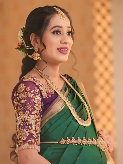 This purple net blouse was a joy to create for my dear client Sowmya's baby shower. The sheer sleeves are adorned with delicate, hand-embroidered floral vines in gold threadwork, creating a look of ethereal elegance for her special day.