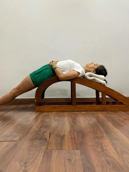 The backbend bench is a specialized prop designed for deep, supported backbends. In this Purvottanasana variation, it provides a firm, contoured surface to open the entire front of the body safely and effectively.