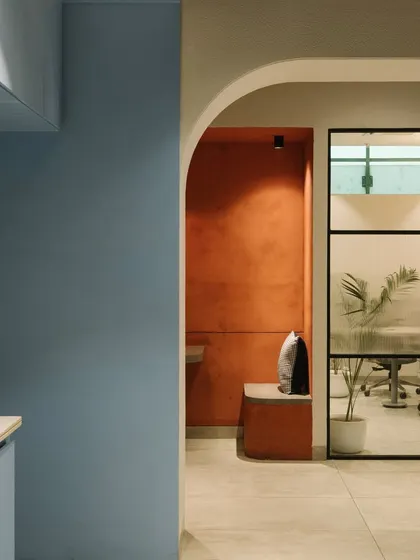 A view from the cafeteria into a breakout nook and a glass-walled meeting room, showing the layered and interconnected design of the office.