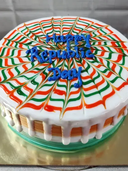 A round Republic Day cake with a spider-web design using the tiranga colors.