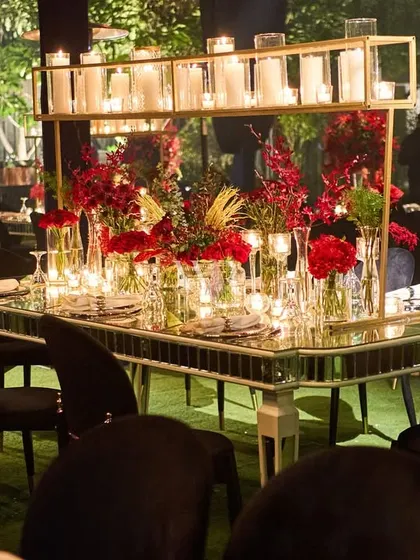 A wider view of the stunning red and candlelit tablescape. The mirrored table creates an illusion of endless flowers and light, making for a truly immersive dining experience.