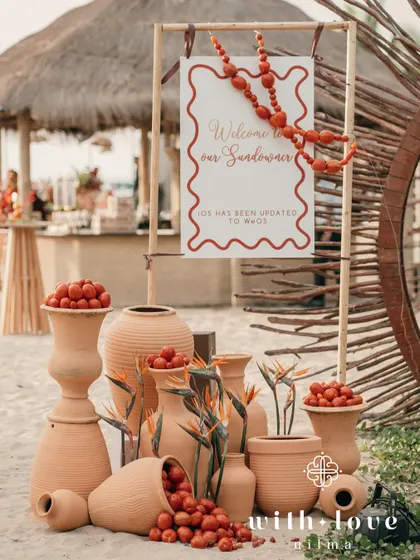 The welcome signage for a tropical sundowner, decorated with terracotta pots filled with cherry tomatoes and birds of paradise flowers.