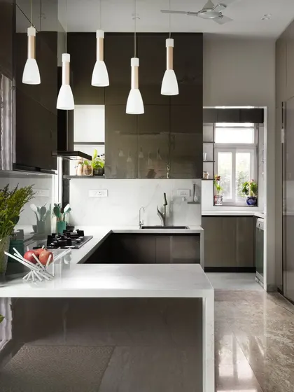 This modern kitchen is the heart of the home, featuring sleek, high-gloss grey cabinetry and a pristine white quartz countertop. The design focuses on clean lines and an efficient U-shaped layout, with integrated appliances and pendant lighting that adds a touch of warmth and style.
