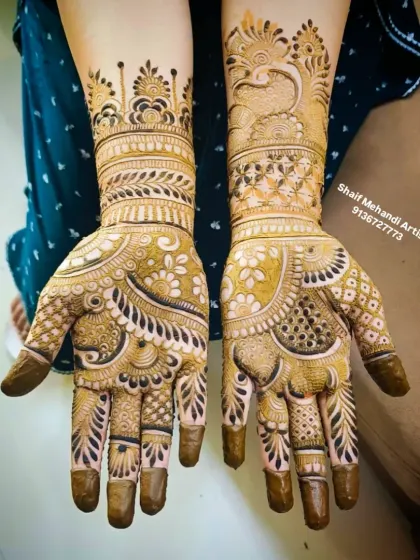 Another angle of the peacock and lotus design, showing how the patterns flow from the palm to the forearm. The solid-colored fingertips are a classic bridal choice.