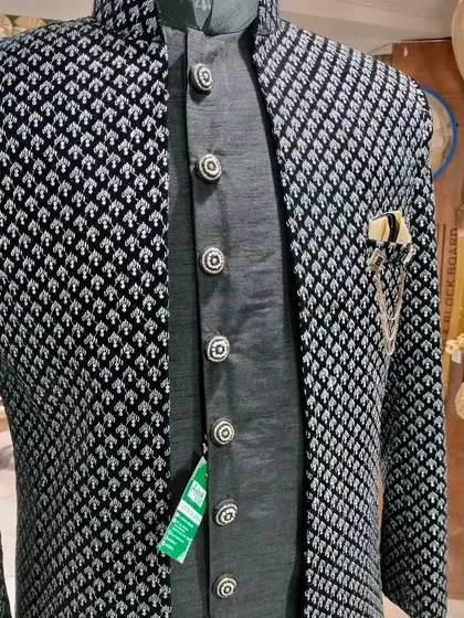 A black and silver patterned Indo-Western jacket with a grey inner kurta. The metallic buttons add a touch of shine to the outfit.