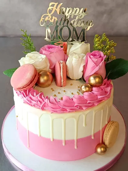 This is the beautiful cake that brought a big smile to a customer's mom. It's a pink and white drip cake decorated with fresh roses and macarons.