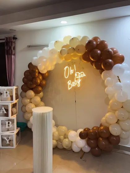 Our 'Teddy Bear Hug' theme is a crowd favorite for its cozy and neutral charm. This baby shower setup features a full ring balloon arch in brown, beige, and white, an 'Oh! Baby' neon sign, a classic cake plinth, and our popular transparent 'BABY' boxes.