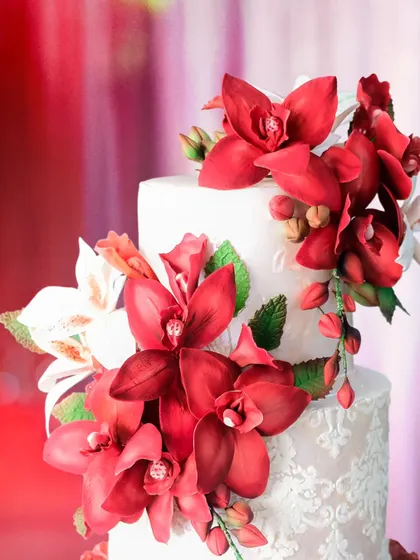 A close-up of the bold, handcrafted scarlet sugar orchids on our 'Dripping Scarlet Love' wedding cake. The vibrant color and intricate detail make this a truly show-stopping design.
