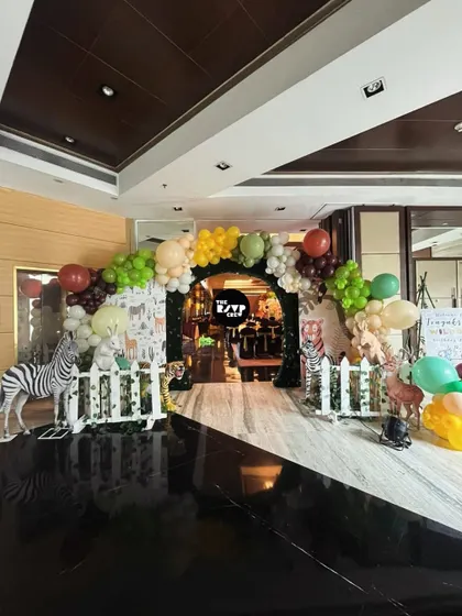 A different take on a jungle entrance, this one features a balloon arch and a path lined with a white picket fence and life-like animal props.