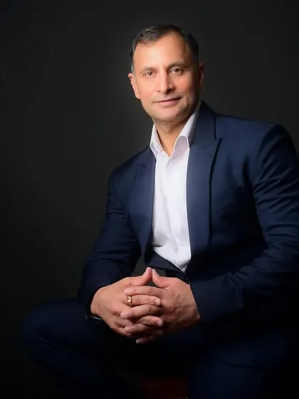 A seated portrait of a politician in a suit. This pose conveys a sense of calm authority and readiness to listen, suitable for official profiles.