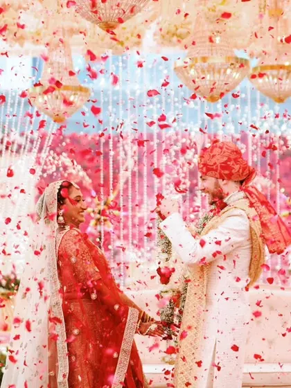 A joyous moment as the couple is showered with rose petals during their wedding ceremony, creating a vibrant and celebratory photograph.
