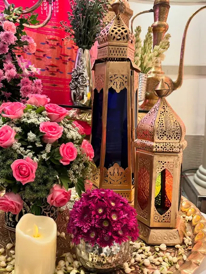 A table centerpiece with pink roses, candles, and ornate Turkish lanterns, creating a warm and inviting glow.