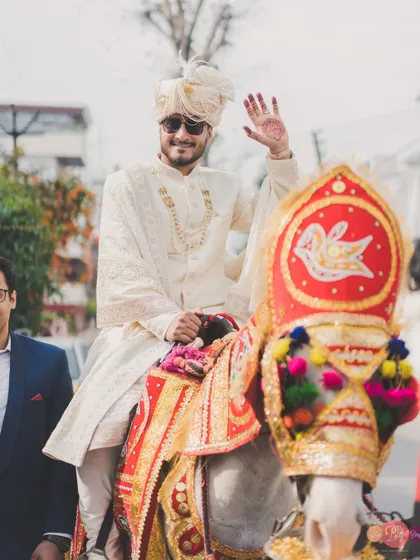The groom's grand arrival. Aditya makes his way to the wedding on a decorated horse, a classic Baraat moment we love to capture.