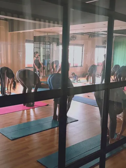 A view from outside the studio during a workshop, as students move through a forward fold.