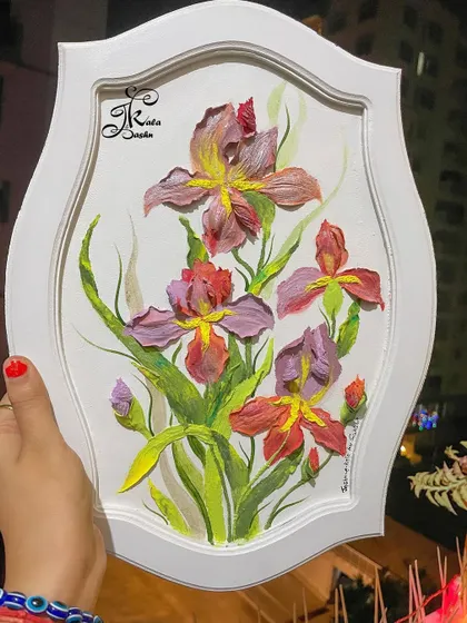 A beautiful wall panel featuring a bouquet of sculpted irises in shades of purple and red, set within an elegant white frame.