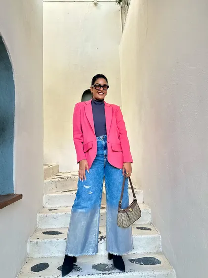 This outfit is a masterclass in mixing styles: a professional blazer, casual jeans, and a luxury handbag.