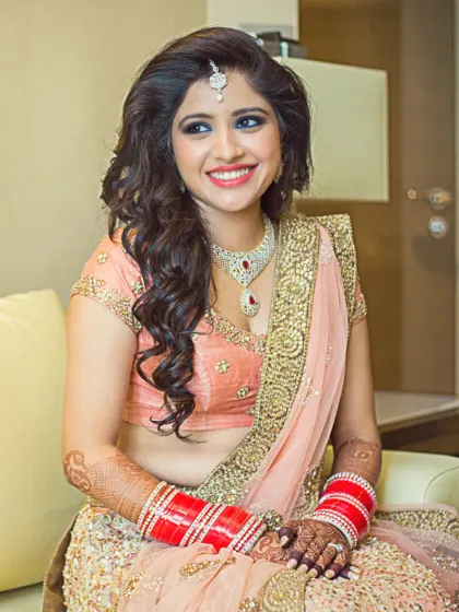 A radiant bride smiles, ready for her big day. This portrait captures her happiness and the beautiful details of her makeup and jewelry.