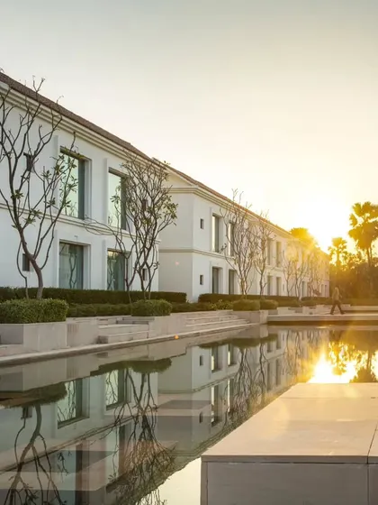 The hotel's guest wings overlook a reflective water body at sunset, a design choice that enhances the sense of calm and connection to nature.