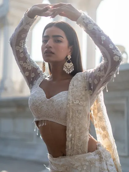 Drench yourself in pure elegance with this ivory lehenga featuring delicate threadwork and a full-sleeve blouse.