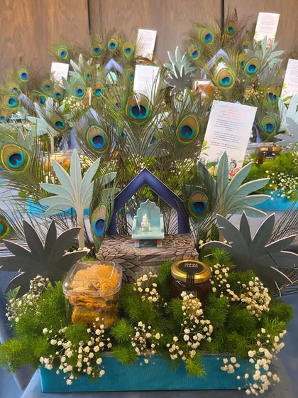 A close-up of one of the 'Little Kanha' hampers, showing the miniature shrine, peacock feathers, and sweet treats.