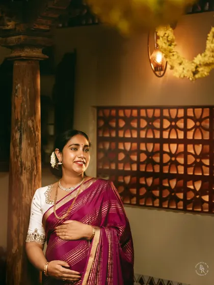 A glowing mother-to-be in a traditional setting. The warm light from the lantern and her happy expression create a serene and joyful maternity portrait.